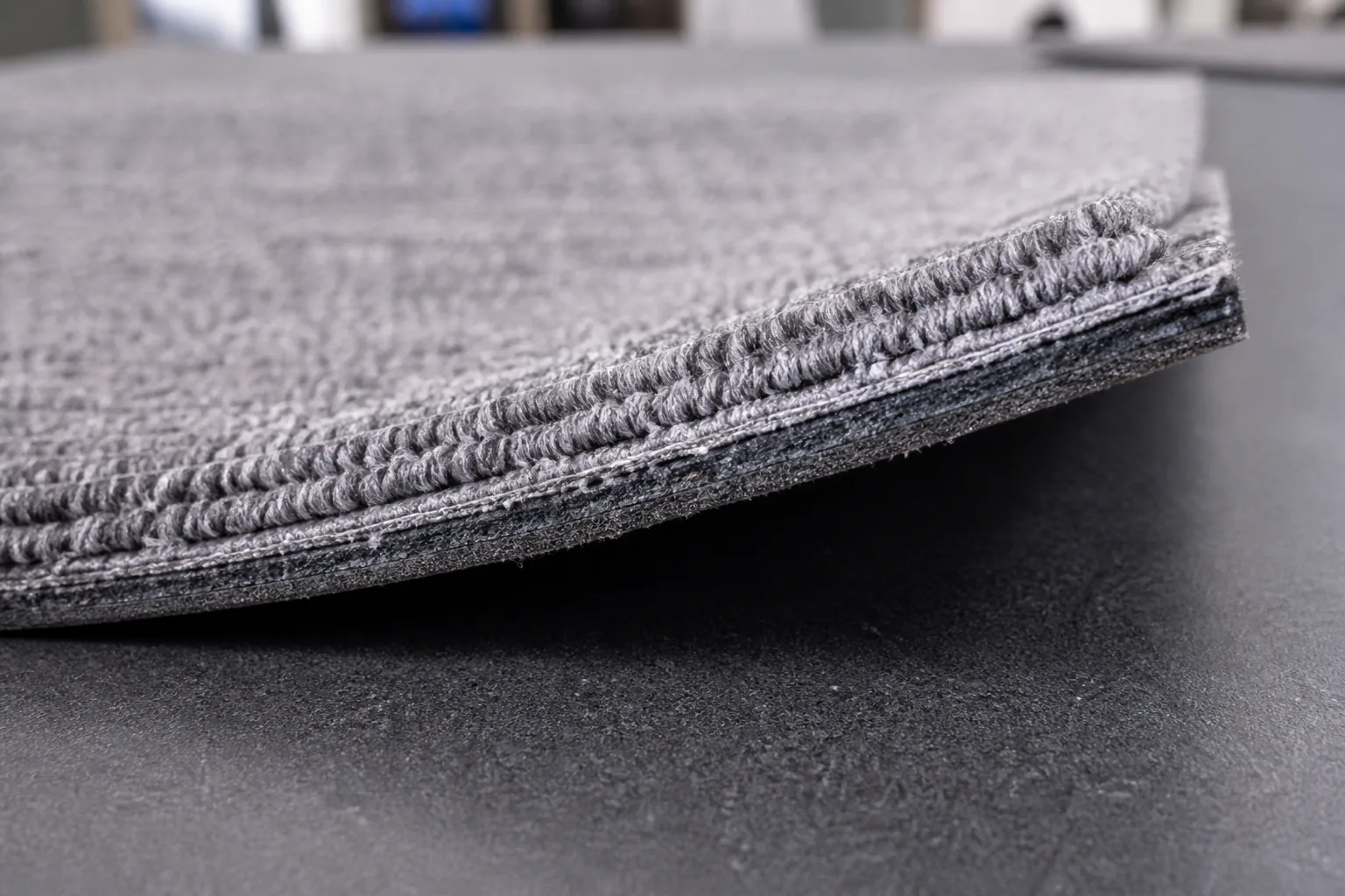 Close-up of commercial carpet tile pile texture and layered backing structure