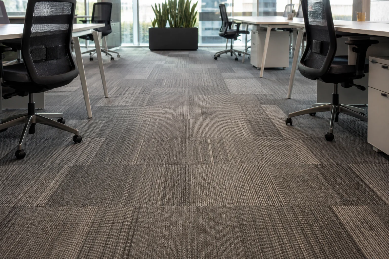 Modular office carpet tiles installed below rolling office chairs in a commercial workstation zone